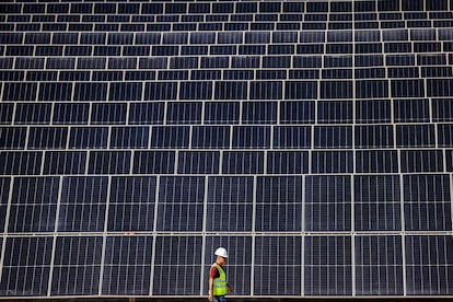 Un hombre emiratí pasa junto a paneles fotovoltaicos en Al Dhafra, al sur de la capital, Abu Dabi (Emiratos Árabes).