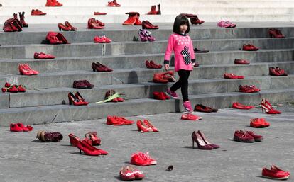 Una ni?a camina entre decenas de zapatos rojos dispuestos sobre unas escaleras como forma de denuncia contra la violencia de gnero, en Tirana (Albania).