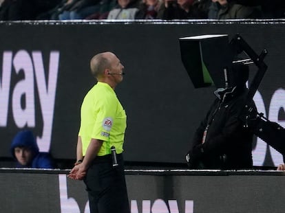 Referee Mike Dean checks the VAR screen during the English Premier League soccer match between Burnley and Manchester United at Turf Moor, in Burnley, England, Tuesday, Feb. 8, 2022.