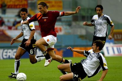 Totti se escabulle con la pelota entre tres defensas del Siena en el partido que perdió ayer el Roma.