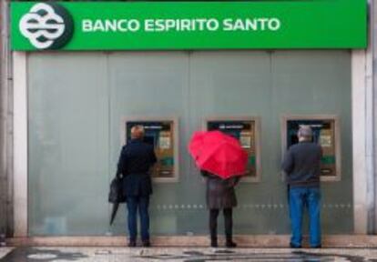 Varios clientes utilizan cajeros autom&aacute;ticos en una oficina de Banco Espirito Santo.