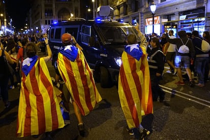 Protesters surround a Mossos patrol car.