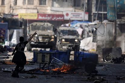 A Palestinian gestures to Israeli military vehicles during clashes in the West Bank city of Nablus, Wednesday, Feb. 22, 2023.