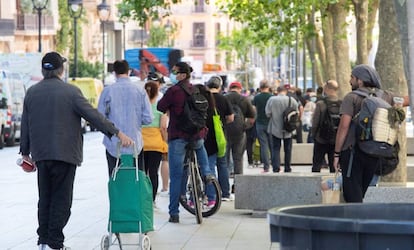 Gent espera per rebre ajuda alimentària de la parròquia Santa Anna, a Barcelona.