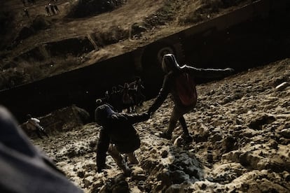 Migrantes caminan hacia la valla fronteriza bajo la vigilancia de las patrullas fronterizas de Estados Unidos, mientras intentan ingresar a San Diego desde Tijuana.