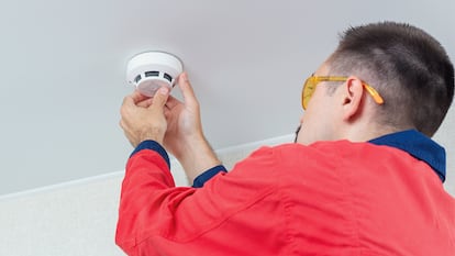 Un hombre instalando un detector de humos.