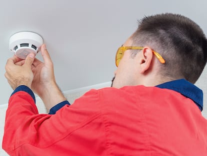 Un hombre instalando un detector de humos.