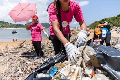 Três dos mais de 2.000 voluntários que limparam uma praia de Hong Kong no último 27 de maio.