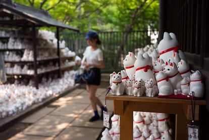 Una turista camina entre las figuritas de "maneki-neko".