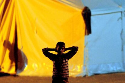 Un niño refugiado sirio permanece a las puertas de las tiendas de campaña instaladas por la Media Luna Roja en el distrito turco de Yayladagi.