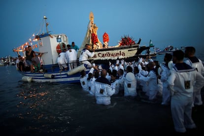 Los marineros comienzan a subir a la barca la imagen de la Virgen del Carmen tras la procesión por las calles de Torremolinos, Málaga.