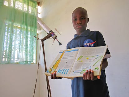 Malick Ndiaye, con 12 años, posa con un viejo libro de su padre con el que aprende astronomía.