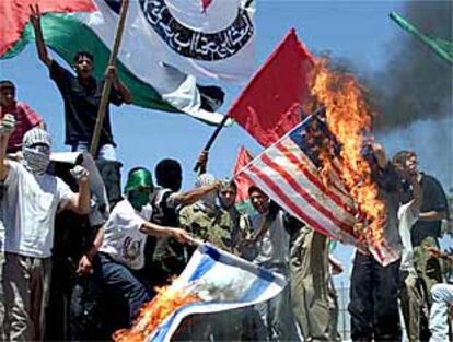 Palestinos enmascarrados queman banderas estadounidenses e israelíes en una protesta en Nablús.