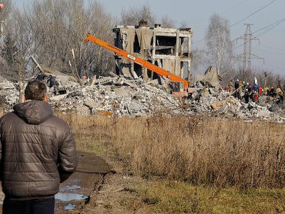 Un hombre observa cómo unos trabajadores retiran los escombros de un edificio donde murieron decenas de soldados rusos esta Nochevieja tras un ataque con misiles ucranianos, en Makiivka, municipio del este de Ucrania controlado por Rusia.