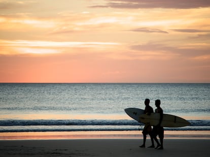 Dos surferos caminan por la Playa Avellana en Costa Rica.