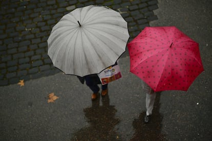 Dos personas con paraguas pasean en un día lluvioso en Pamplona.