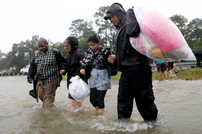 Una familia camina por el agua tras ser rescatada, el lunes.