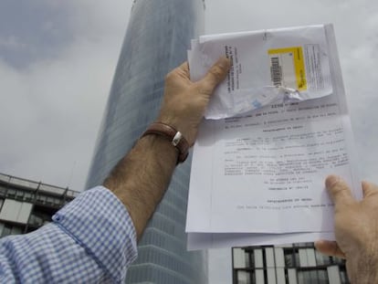 J. C. M. exhibe la sentencia ante la Torre Iberdrola de Bilbao, donde se encuentra la sede de Aenor.