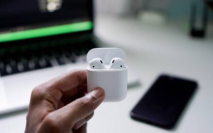 Un hombre sujeta los auriculares 'true wireless' AirPods V2, de la marca Apple.