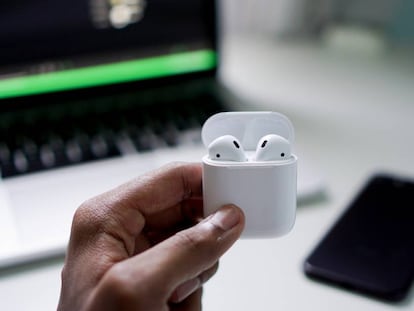 Un hombre sujeta los auriculares 'true wireless' AirPods V2, de la marca Apple.