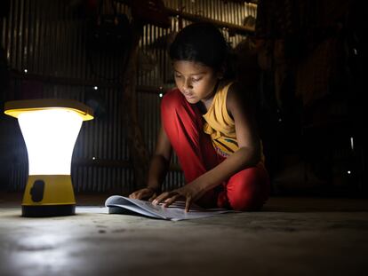 Una niña lee en su casa utilizando una luz de energía solar en Jaliyapalong, Cox's Bazar, Bangladés.