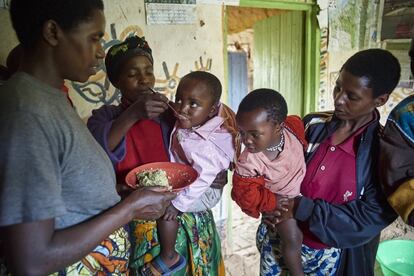 Unicef y sus aliados están apoyando los esfuerzos del Gobierno para proporcionar intervenciones nutricionales integradas en Ruanda, donde el 38% de los menores de cinco años padece retraso en el crecimiento, uno de los mayores desafíos de desarrollo que enfrenta el país. En la imagen, una mujer alimenta con cuchara a su hija de un plato que sostiene un trabajador de salud comunitario, durante una manifestación en una reunión del Grupo de atención de asesoramiento nutricional en la aldea de Uwabumenyi, en el distrito de Nyamagabe. La comida se ha enriquecido con un polvo de micronutrientes.