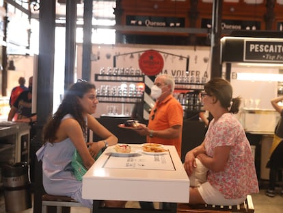 Dos mujeres comen en la mesa de un puesto del Mercado de San Miguel en su reapertura, el 1 de julio.