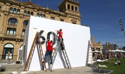 Dos trabajadores colocan el cartel del festival de San Sebastián