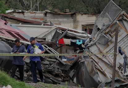 Dos trabajadores de la Fiscalía local inspeccionan el sitio del descarrilamiento en Tala, el 15 de junio