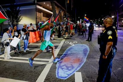Un hombre salta sobre una proyección de la cara de Joe Biden, durante la protesta propalestina en Atlanta.