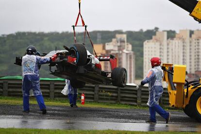 El coche de Romain Grosjean es sacado por una grúa tras colisionar contra la valla.