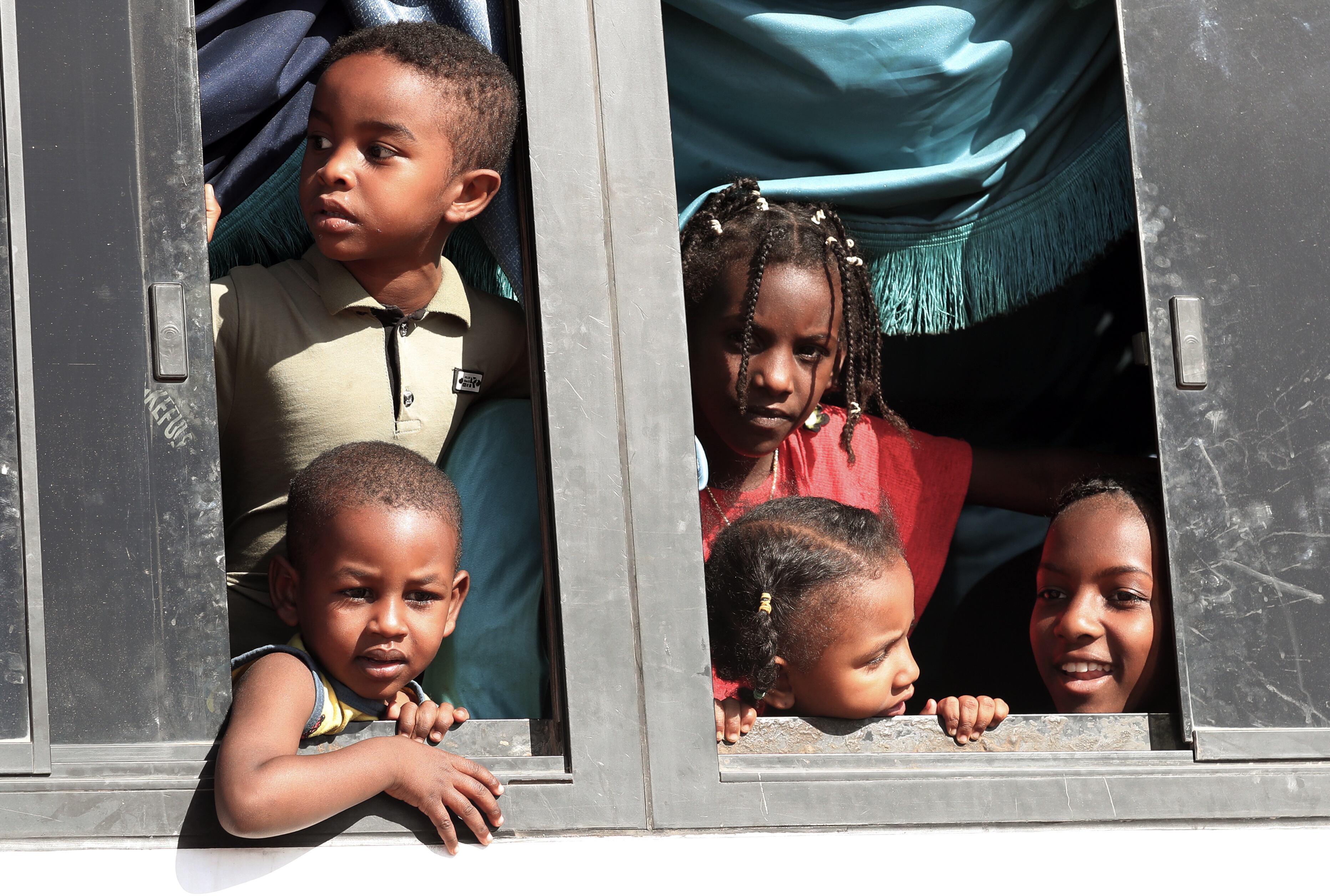 Varios niños sudaneses subidos en un autobús atraviesan el río Nilo en un transbordador tras cruzar la frontera desde Sudán, en Abu Simbel, sur de Egipto, el 20 de mayo de 2023. 