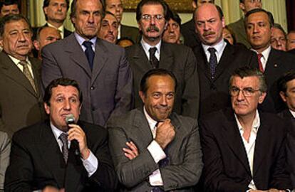 El presidente provisional, Ramón Puerta (izquierda), anuncia que Rodríguez Saá (centro) le sustituirá en la jefatura del Estado.