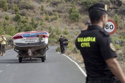 Unos vecinos sacan una embarcación de La Restinga en presencia de la Guardia Civil.