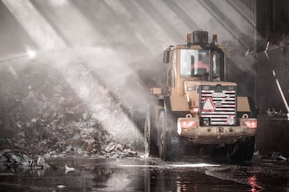 Una excavadora despeja los escombros provocados por un incendio en un almacén de la empresa de papel IOK Afvalbeheer, en Meerhout (Bélgica).
