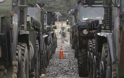 Marines estadounidenses pasan por delante de una filas de vehículos militares.