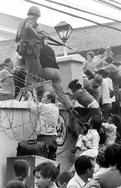 Un grupo de personas trata de entrar en la embajada americana en Saigón saltando el muro exterior para acceder a los helicópteros que evacuaban a los americanos de Vietnam. (29/04/1975)