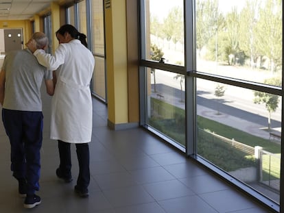 Una especialista ayuda a caminar a un enfermo de alzheimer en el centro CRE de Salamanca.