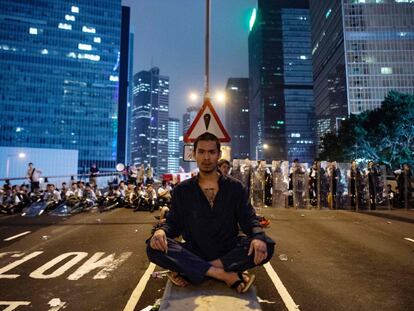 Un hombre protesta la ley de extradición en Hong Kong se sienta frente a un grupo de policías.