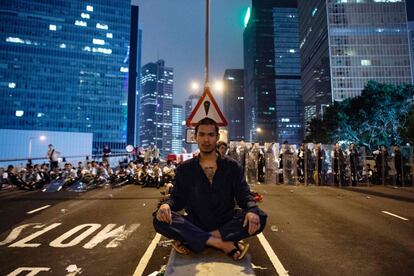 Un hombre protesta la ley de extradición en Hong Kong se sienta frente a un grupo de policías.