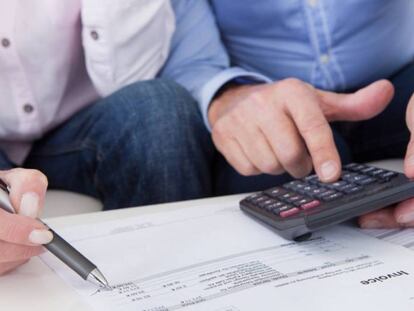 Dos personas utilizan una calculadora mientras revisan una factura.