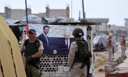 Militares rusos en un 'checkpoint' con un póster de El Asad y Putin, en el oeste de Siria.