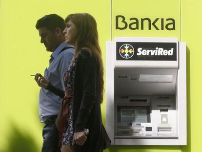 Dos personas pasan frente a un cajero de Bankia.