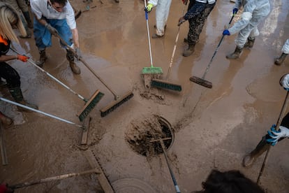 Varias personas tiran el barro a una alcantarilla de Alfafar, el 9 de noviembre. 