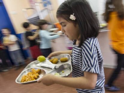Una ni&ntilde;a lleva una bandeja de comida en un colegio de Barcelona