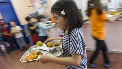 Una ni&ntilde;a lleva una bandeja de comida en un colegio de Barcelona