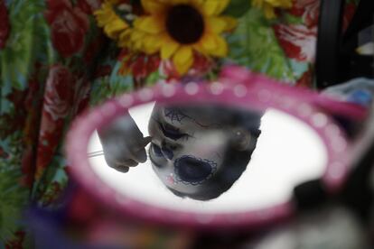 Una joven termina su maquillaje como Catrina para prepararse para el desfile en Ciudad de México.