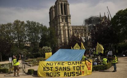 Un cartel lee: "Notre Dame está sin techo, nosotros también", en París.