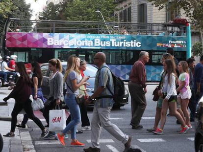 Paseantes en una céntrica calle de Barcelona, con un autobus turístico al fondo