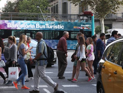 Paseantes en una céntrica calle de Barcelona, con un autobus turístico al fondo